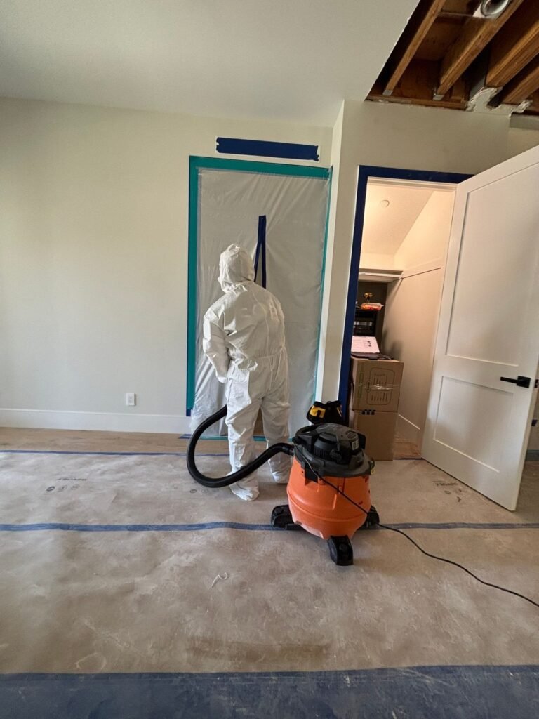 A technician vacuuming in a living room with the ceiling opened above in the East Bay