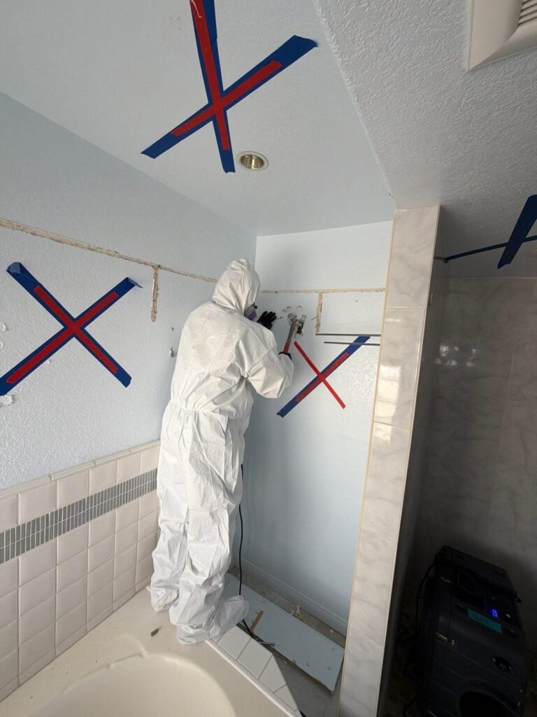 A technician working in a bathroom marked with large red and blue cut lines in the East Bay