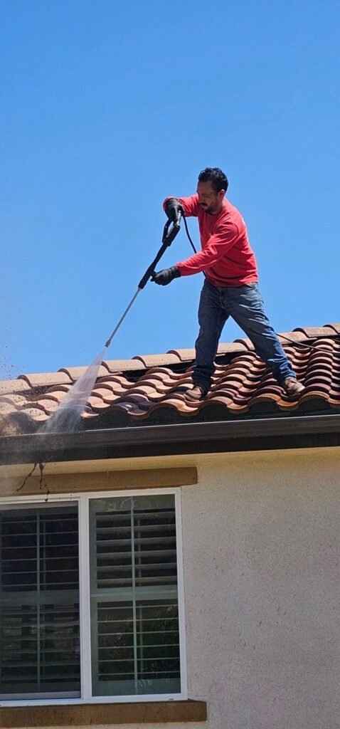 A worker pressure-washing a tile roof in the East Bay