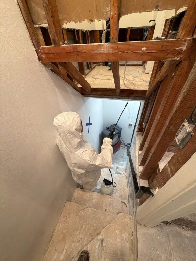 A technician working beneath a ceiling opened to the joists in the East Bay